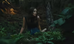 young woman sitting in the woods while staring out