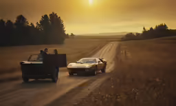 two cars with people on the bed drive down a dirt road
