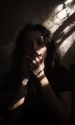 a woman holding her hands in front of her face
