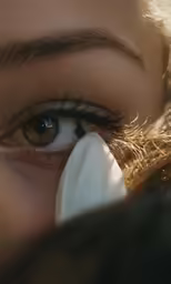 the eye of a woman covering her face with tissue paper