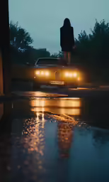 a woman walks down the street in a rainy day, while traffic passes