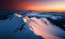 snow covered mountains at sunset with clouds around them