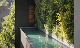this indoor swimming pool has green plants on the side