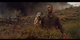a man is holding his dog in a field
