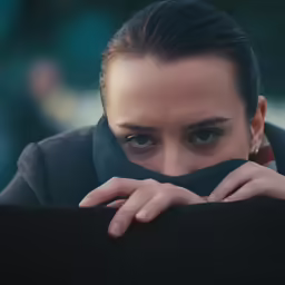 a close up of a person behind a pillow
