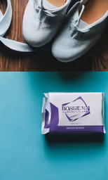 a package of white shoes sitting next to two pairs of shoes on top of a table