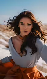 a woman sitting on the beach with her hair in the wind
