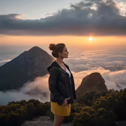 a woman is standing on top of a mountain in the clouds