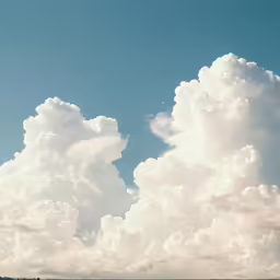 a group of people walking down a field under clouds
