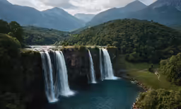 waterfall near grassy area with trees and water