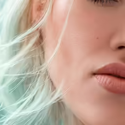 a blond woman with eyes closed, with long, wavy hair and bare lips