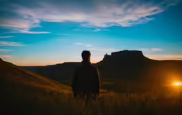 a man standing in a field at sunset