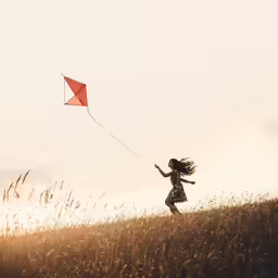a girl is flying a kite in a field