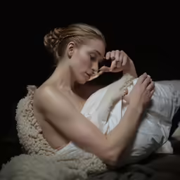 a girl is sitting on her bed looking at a fluffy white jacket