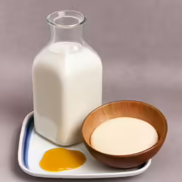 a bottle of milk next to a wooden bowl on a plate