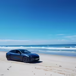 the black car is parked on the beach by the water