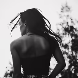 a young woman wearing a strapless dress with her hair blowing in the wind
