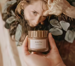 there is a woman that is holding a jar of cream