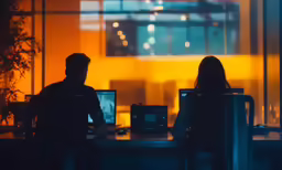 two people sitting at a desk facing each other