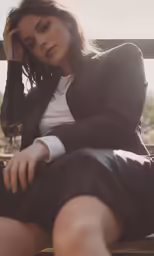 a woman in suit and shirt sitting on top of a wooden bench