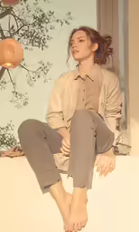 a woman sits on the ledge of an outdoor building and looks forward