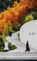 a group of people walking across steps next to a water wall