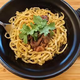 a bowl filled with noodles and meat covered in sauce