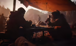 two people at a table eating food under an umbrella