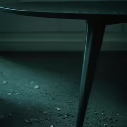 an artistic black table with wavy legs in a dimly lit room