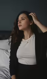 a woman sitting on a bed in black and white