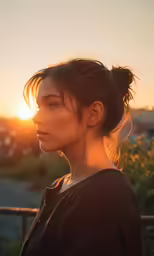 a woman is looking at the sunset and she has her hair in a high bun