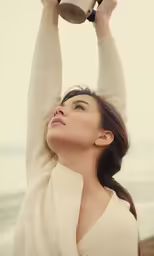 a woman is holding her cup in the air