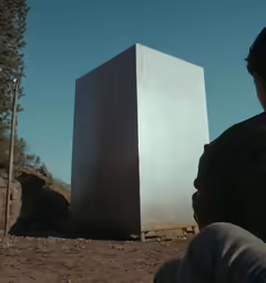 the man is sitting down next to his building