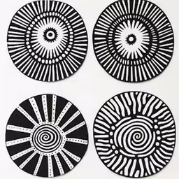 a group of four circular black and white paper cutout pictures,four black and white circles made out of a piece of paper