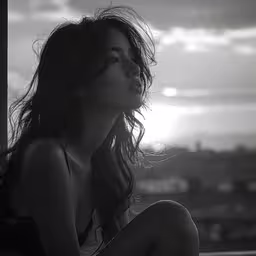a woman is sitting down looking over a city,a woman in a bikini looks out of the window
