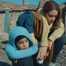 a woman in blue and brown jacket next to a little boy