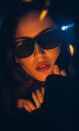a woman wearing dark shades holding a cell phone