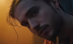 a man with long hair is sitting in the dark