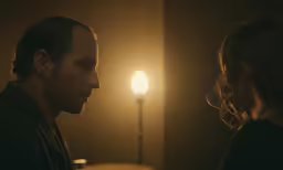 a man with a beard sitting next to a woman in front of a light