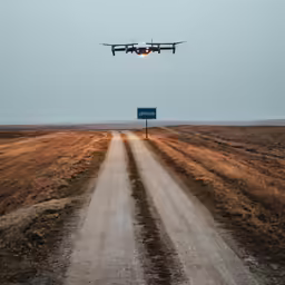 an airplane flying low over a road with a sign in front