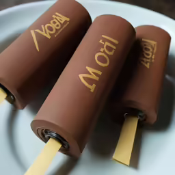 three rolls of chocolate covered bread on top of a plate