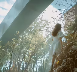 the girl is standing near bushes with her hair down