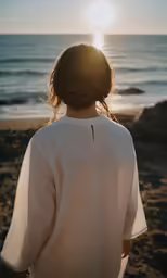a woman is walking along the beach towards the water