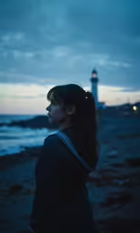 a woman looking into the distance as a light house stands in the background