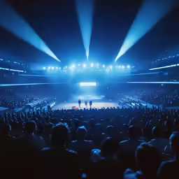 a photo taken from the stage in the middle of an arena at a concert with lights streaming down