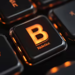 a close up of a black keyboard with an orange b