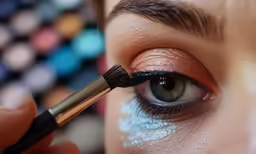 woman using makeup brush to make eyeliner look shiny