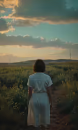 a woman in a white dress is walking through a field