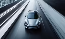 the front end of a silver car driving on a street