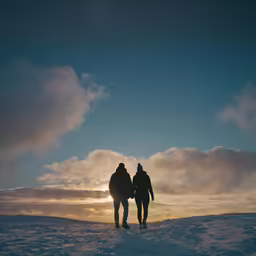 a man and woman are walking together across snow